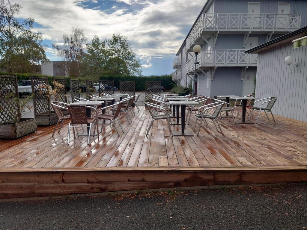 a wooden deck with tables and chairs on it at Fasthotel Angers Beaucouzé in Beaucouzé