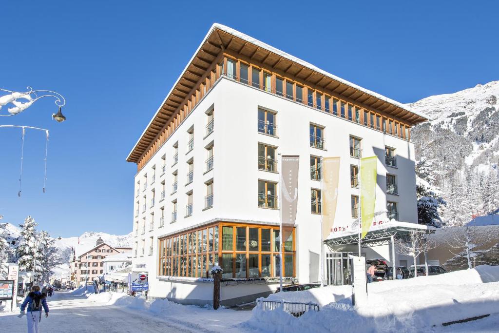 un bâtiment dans la neige devant une montagne dans l'établissement Hotel Allegra, à Pontresina