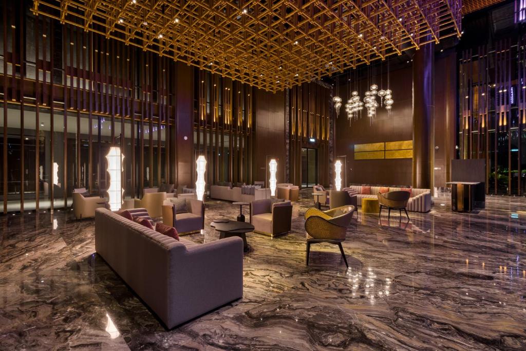 A richly decorated lobby seating area with marble flooring, sculptural lights, and a gold ceiling grid.