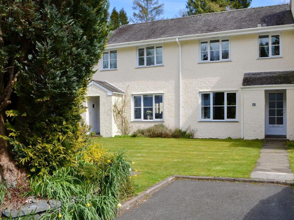 a large white house with a grass yard at Meadowcroft Cottage in Bowness-on-Windermere