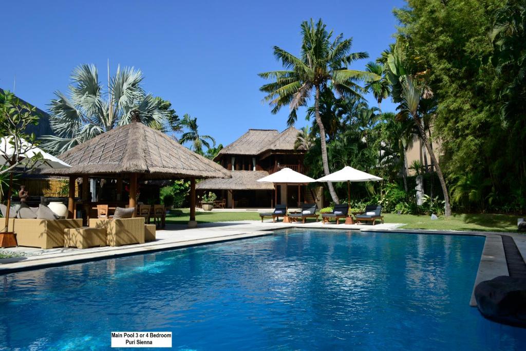 a resort swimming pool with chairs and umbrellas at Sienna Villas - CHSE Certified in Seminyak