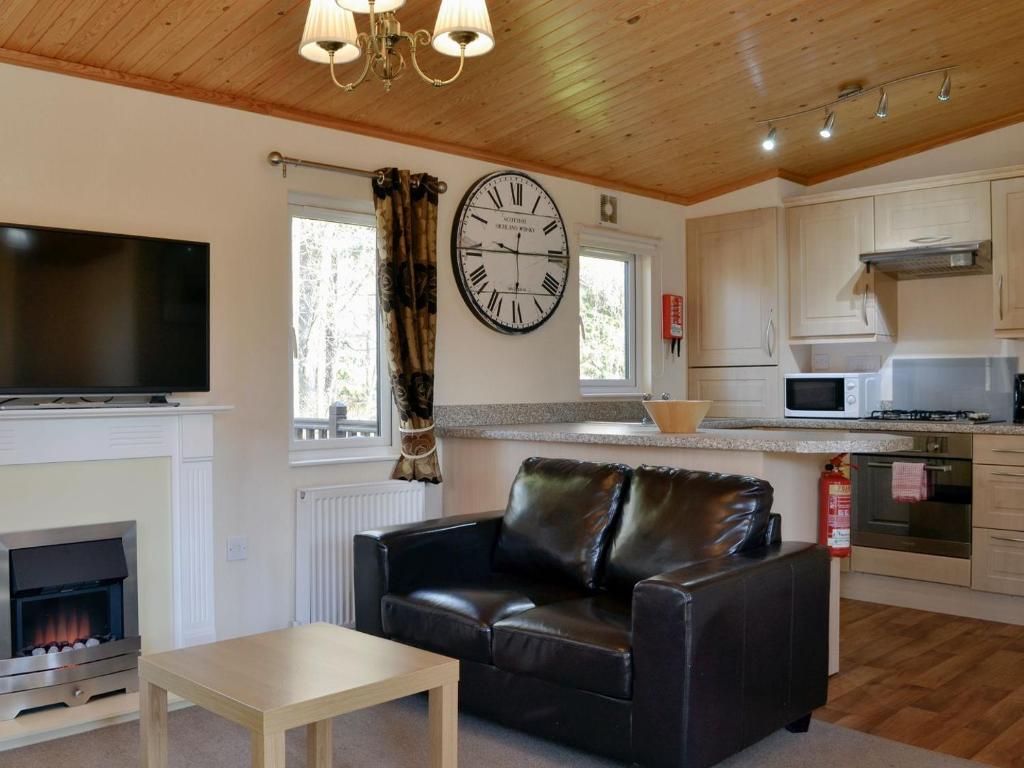 ein Wohnzimmer mit einem Sofa und einer Uhr an der Wand in der Unterkunft Lodge F- Uk33092 in Dinnet