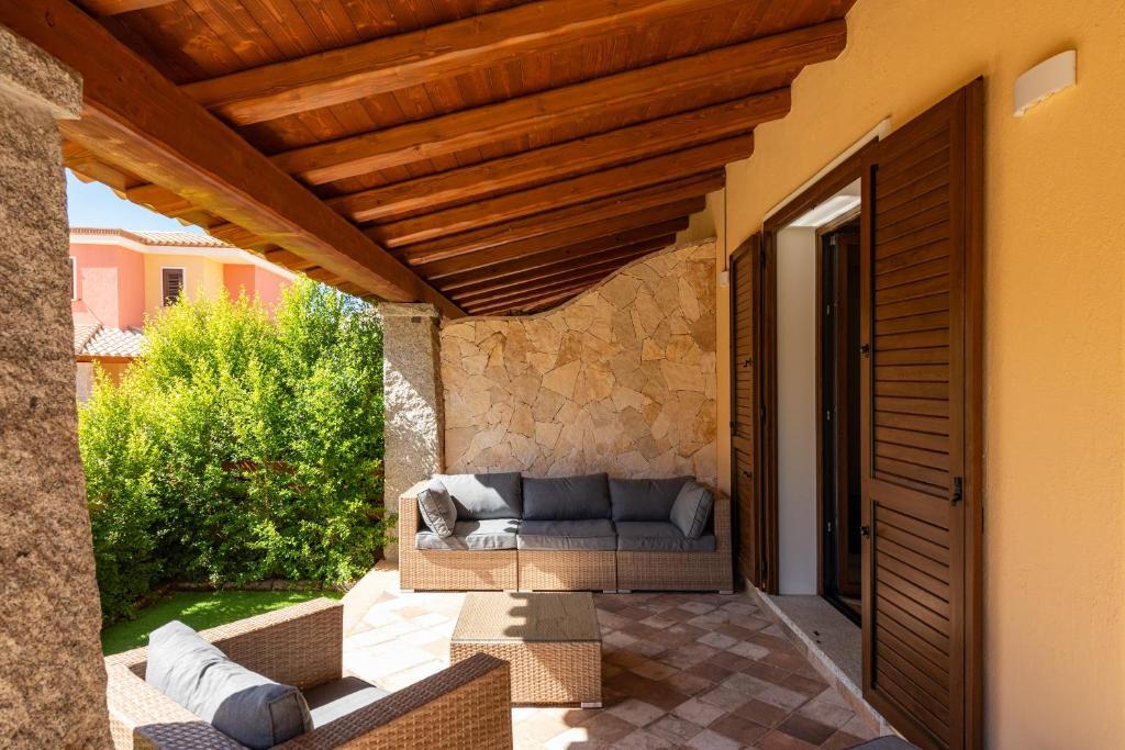 eine Terrasse mit einem Sofa unter einem Holzdach in der Unterkunft Villa Max in Villasimius