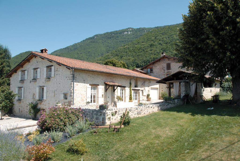 uma grande casa de pedra com uma colina ao fundo em L'Estapade des Tourelons em Saint-Jean-en-Royans