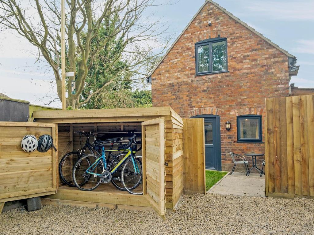 a wooden shed with bikes in it in front of a house at Coley Cottage in Wainfleet All Saints