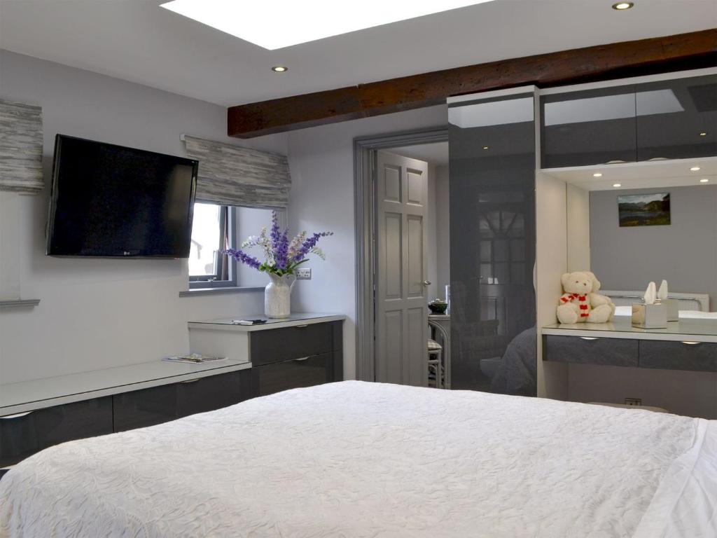 1 dormitorio con 1 cama blanca grande y baño en The Milking Parlour - Uk30866, en St Bees