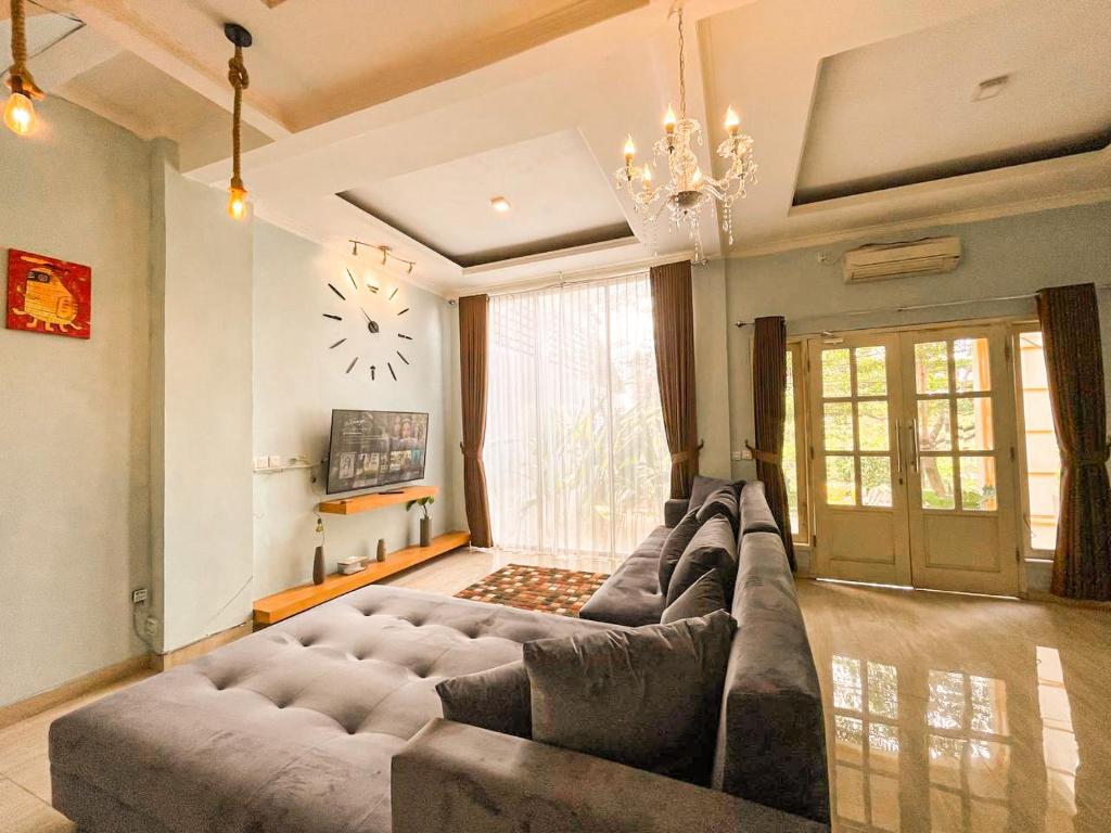 a living room with a large couch and a clock on the wall at Villa Kamar Tamu Warungboto in Timuran