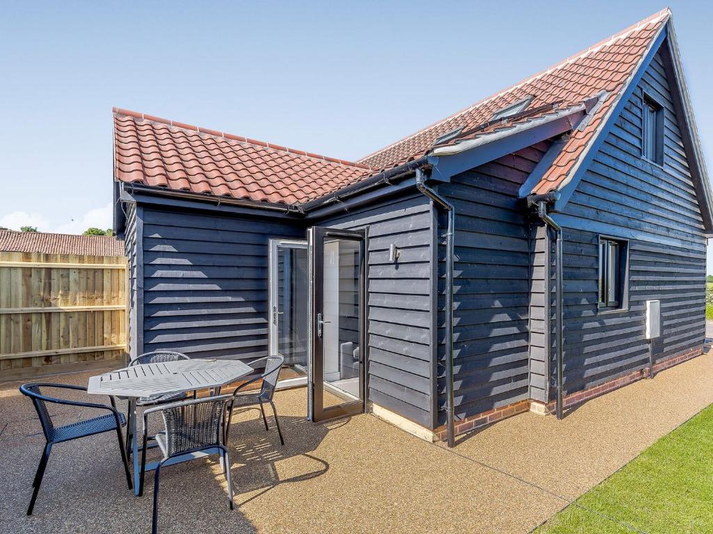 a blue house with a table and a patio at Blackberry Cottage in Stowmarket