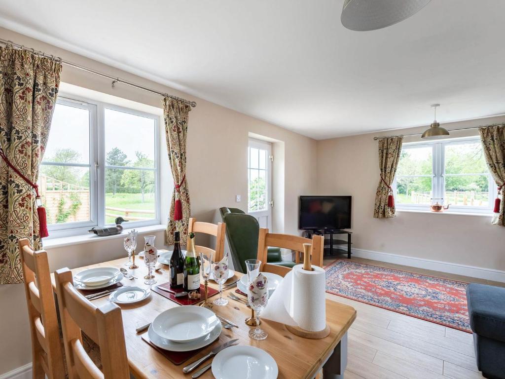 a dining room with a table and chairs and windows at Orchard Barns in North Nibley