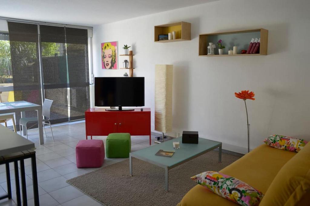 Il comprend un salon doté d'un canapé et d'une télévision à écran plat. dans l'établissement F3 climatisé-terrasse 30 m2- Parking-Antigone, à Montpellier