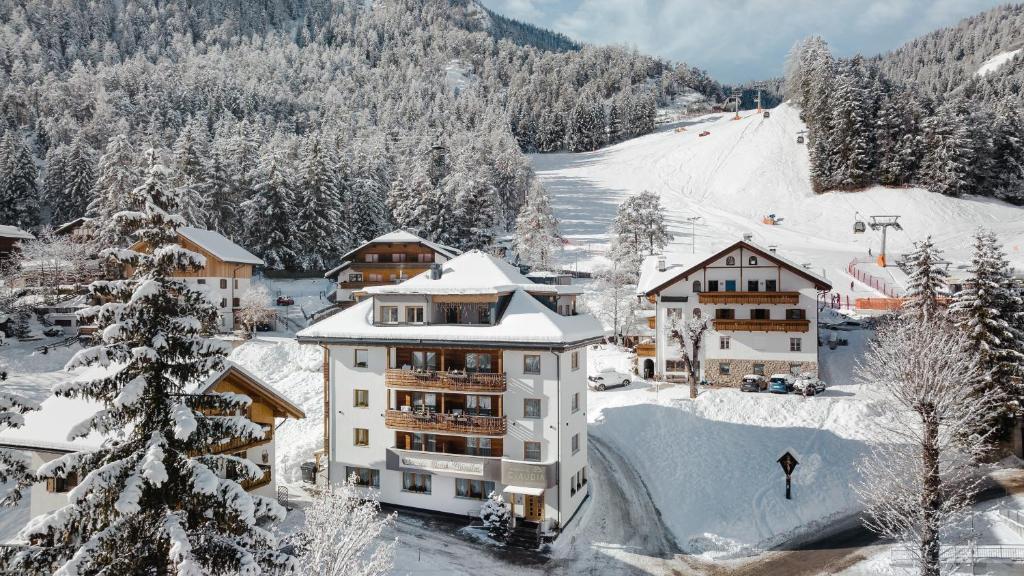 un edificio nella neve con pista sciistica di Piccolo Hotel Claudia No Pets a San Vigilio Di Marebbe