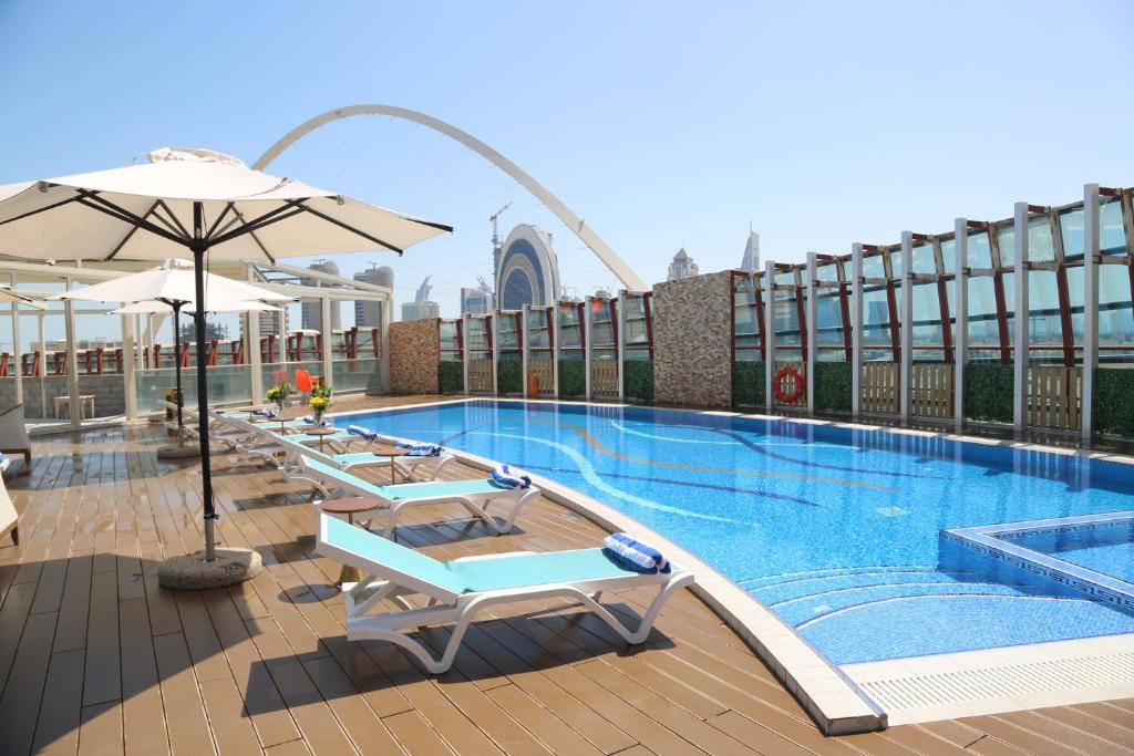 a swimming pool with chairs and umbrellas on a building at Cielo Hotel Lusail Qatar in Doha