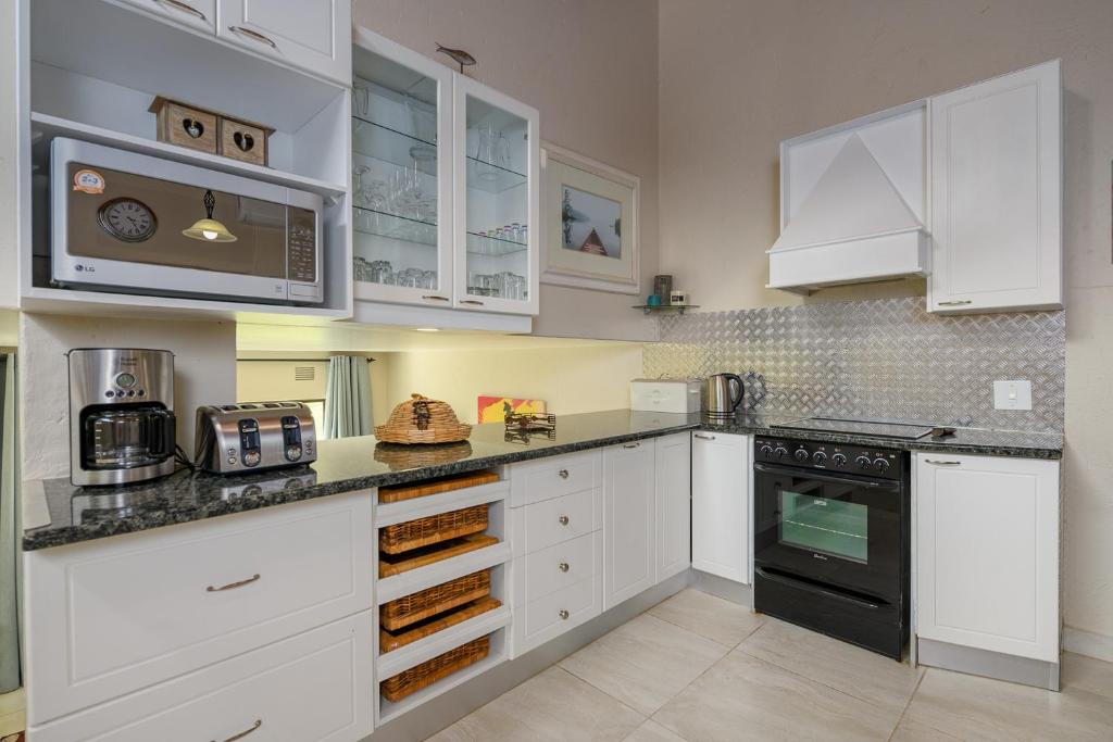 een keuken met witte kasten en zwarte apparaten bij San Lameer Villa 3104 - 3 Bedroom Superior - 6 pax - San Lameer Rental Agency in Southbroom