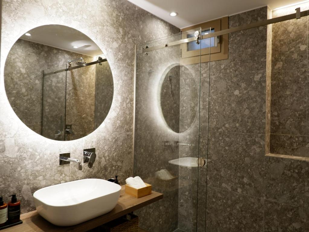 a bathroom with a sink and a shower with a mirror at Kaiser Luxury Suites in Achílleion