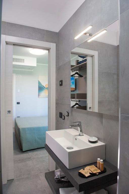 a bathroom with a sink and a mirror and a bed at B&B Lough in Colà di Lazise
