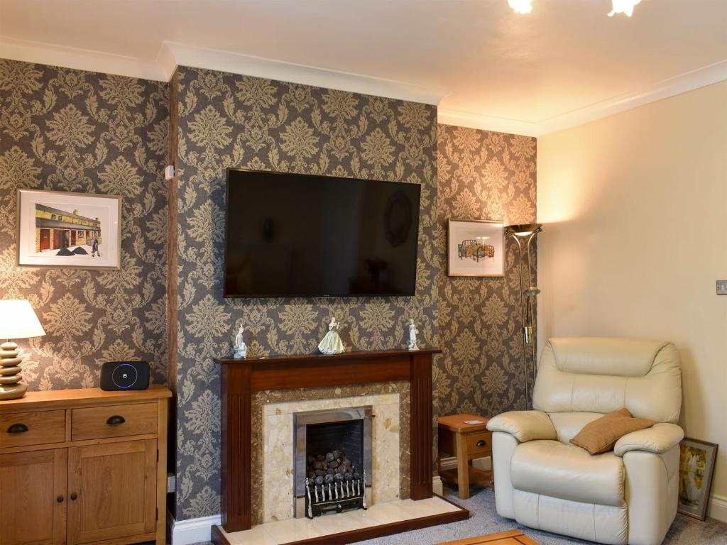 a living room with a fireplace and a television at End Cottage in Alnwick