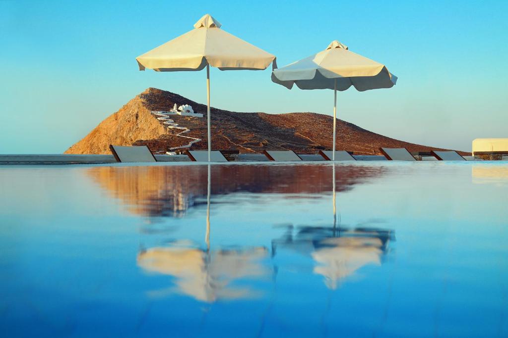 two umbrellas and chairs sitting in the water at Miramare Hotel in Chora Folegandros