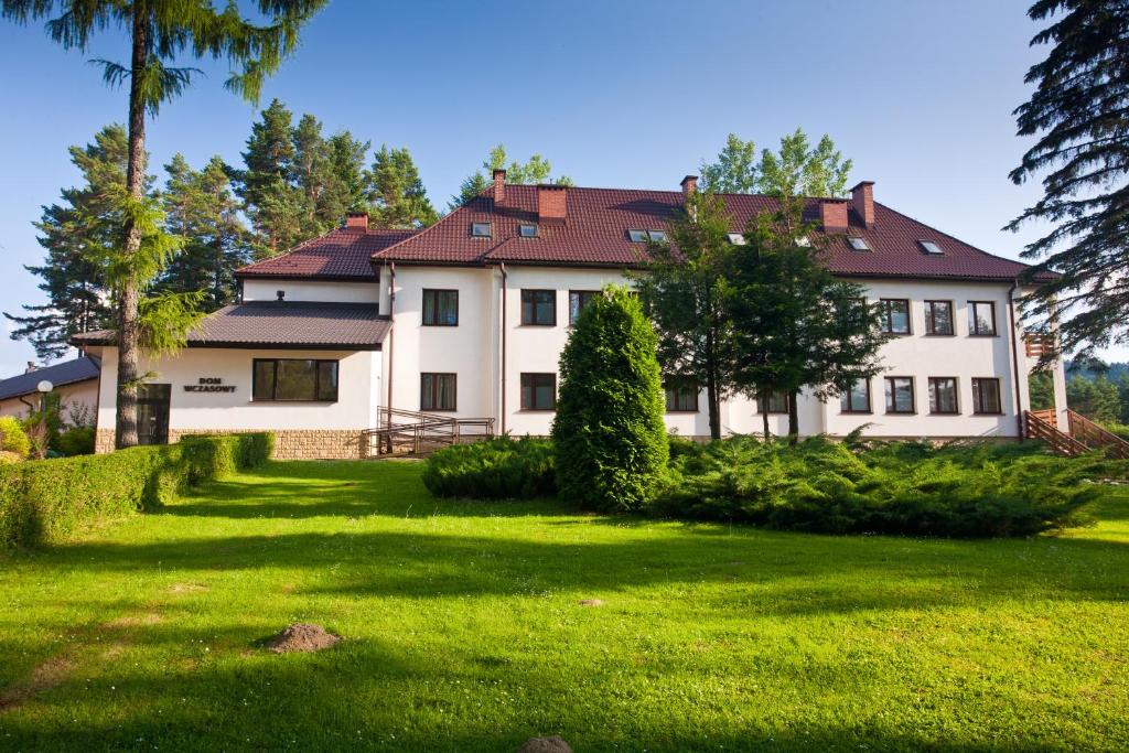 een groot wit huis met een groene tuin bij Perła Bieszczadów - Dom Wczasowy in Czarna