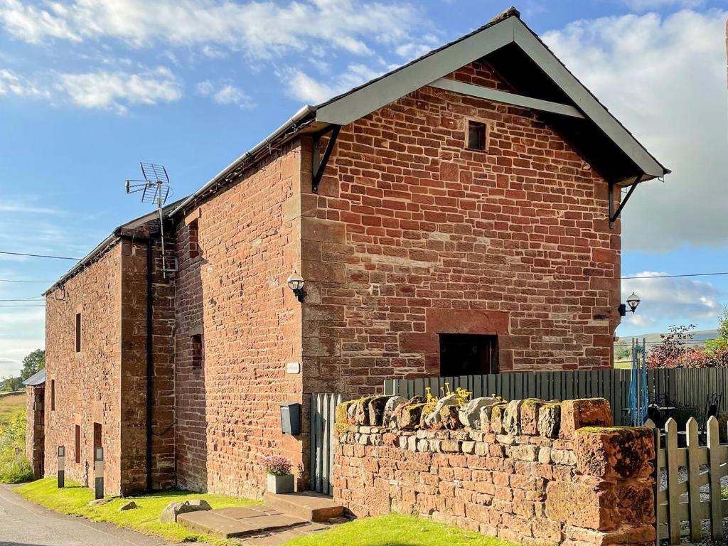 a brick building with a fence in front of it at Helm View in Blencarn