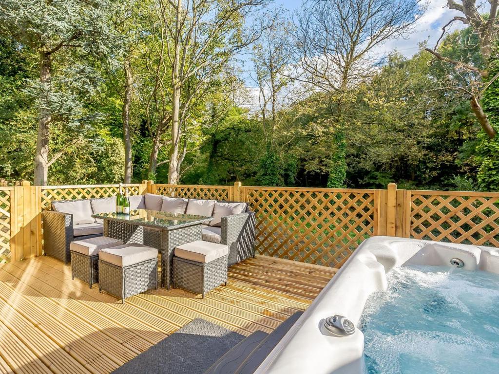 a deck with a hot tub and a table and chairs at Waterside Lodge One - Uk33351 in Southowram