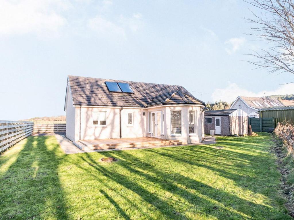 ein kleines weißes Haus mit einem großen Hof in der Unterkunft West Burnside Beach Cottage in Tayinloan