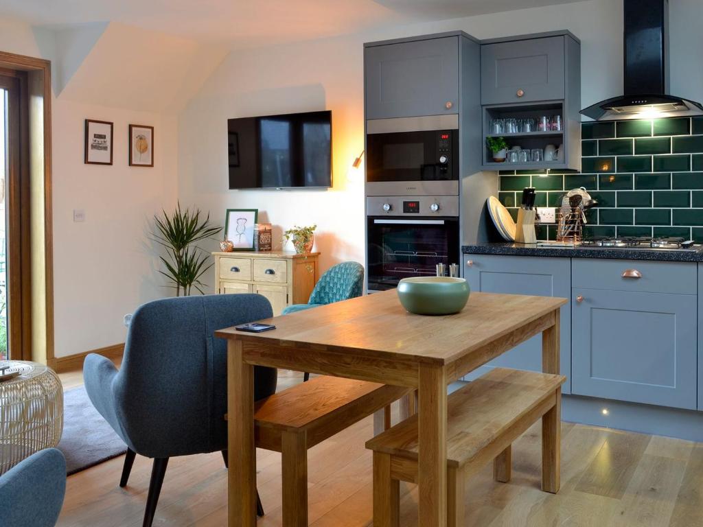 a kitchen with a wooden table and blue cabinets at Howe Cottage in Laurencekirk