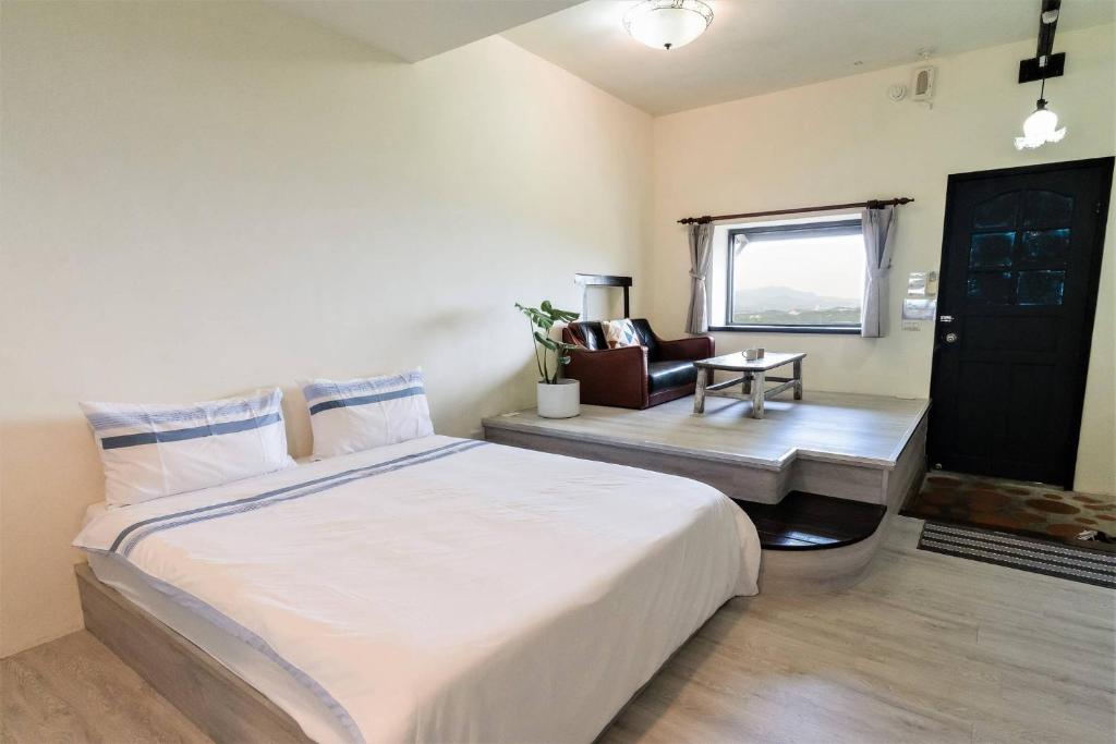 a bedroom with a large white bed and a chair at Sunny Room in Jiufen