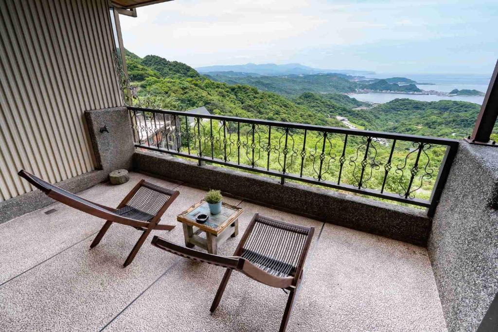 two chairs and a table on a balcony with a view at Sunny Room in Jiufen