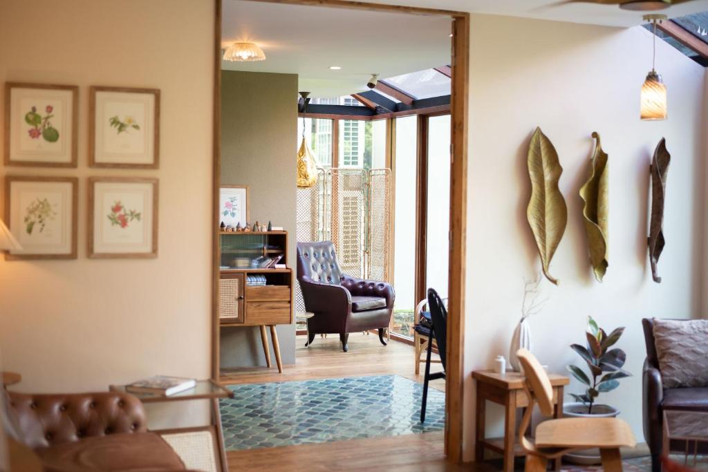 A layered lounge interior with armchairs, a writing desk and a view through to a bright glazed area.