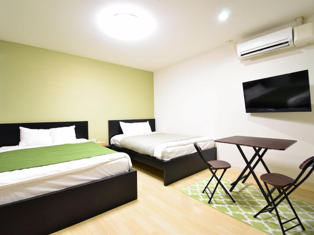 1 dormitorio con 2 camas, escritorio y TV en Regariain - Vacation STAY 84627, en Okayama