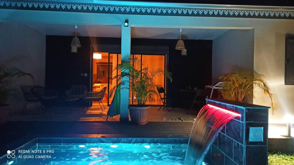 a swimming pool in front of a house at night at Villa Les Jardins de la Trinité in Saint-Philippe