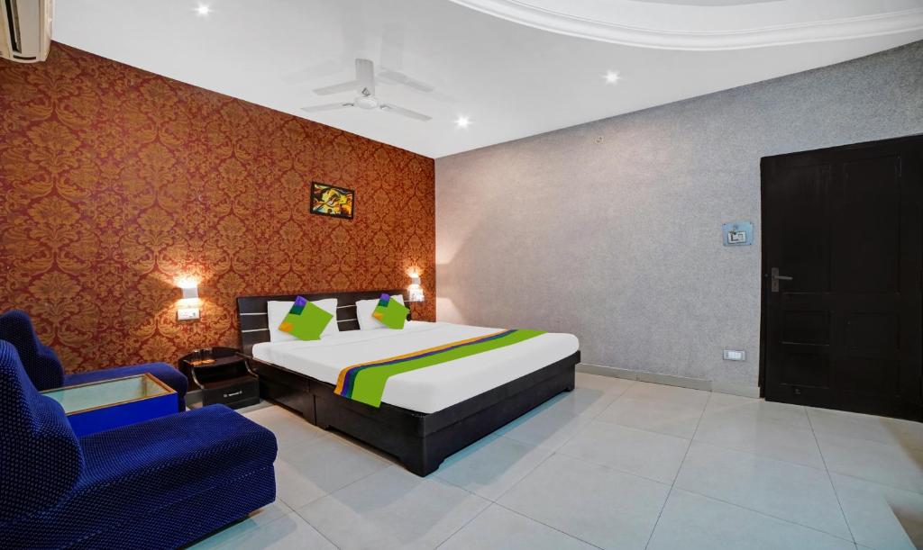 a bedroom with a bed and a blue chair at Treebo Trend MP Inn in Raipur