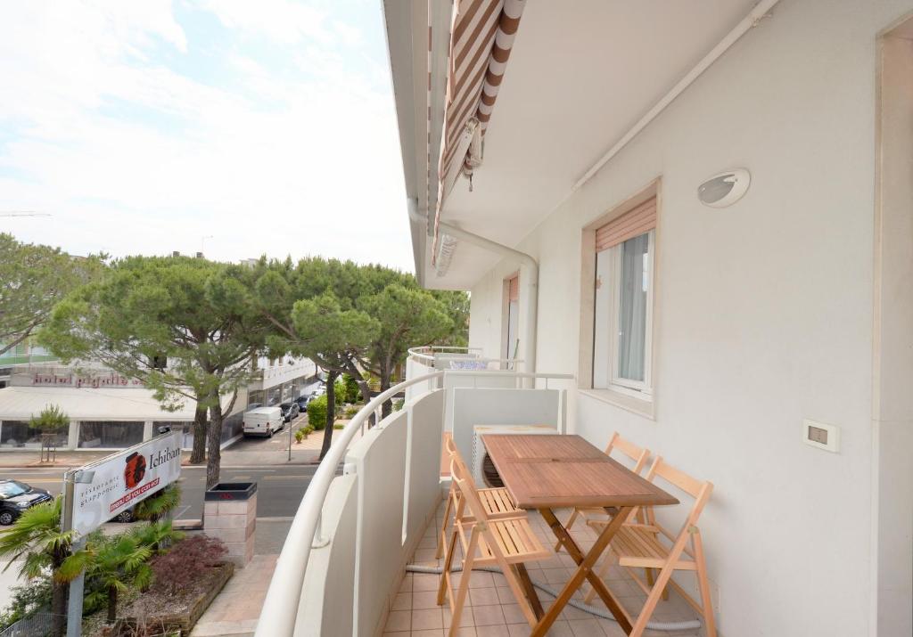 een balkon met een houten tafel en stoelen bij Magica Immobiliare - Doge 22 in Lido di Jesolo