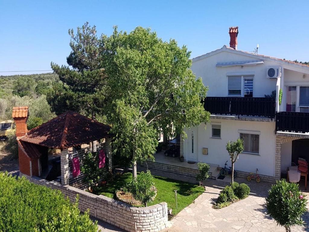 a white house with a tree in the yard at Apartments Snježana Carev in Jezera