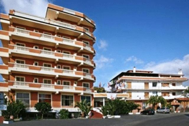 um grande edifício de apartamentos ao lado de um parque de estacionamento em Hotel Casa Del Gourmet em Siderno Marina
