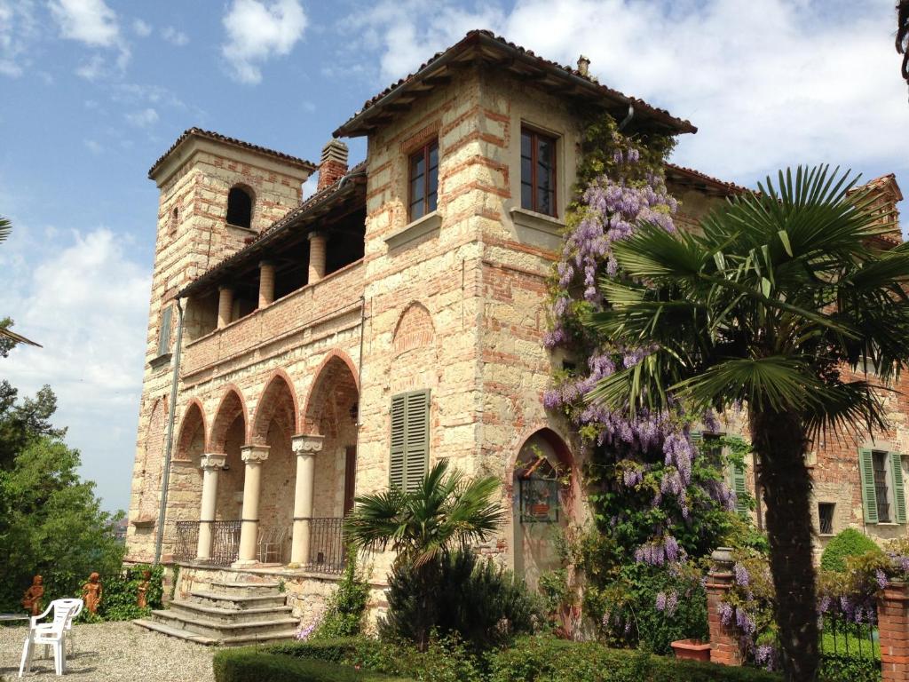 an old stone house with purple flowers on it at Castello Di Frassinello in Frassinello Monferrato