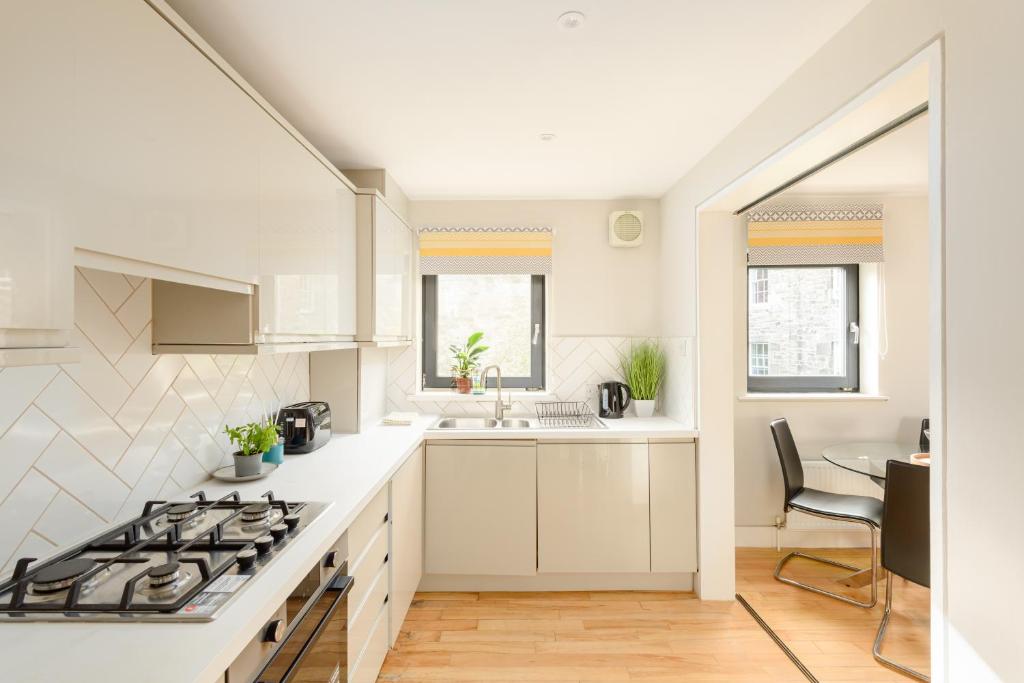 a kitchen with white counters and a stove top oven at Modern Mews Apartment - New Town in Edinburgh