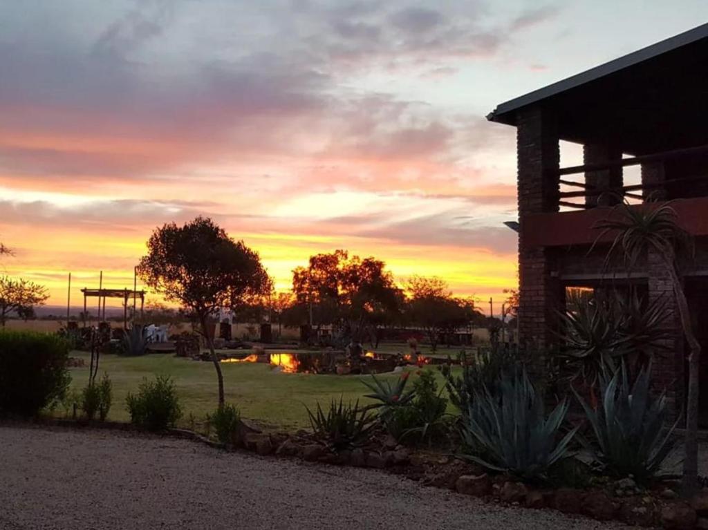 een uitzicht op de zonsondergang van een park met een gebouw bij Nyani Lodge Dinokeng in Pretoria