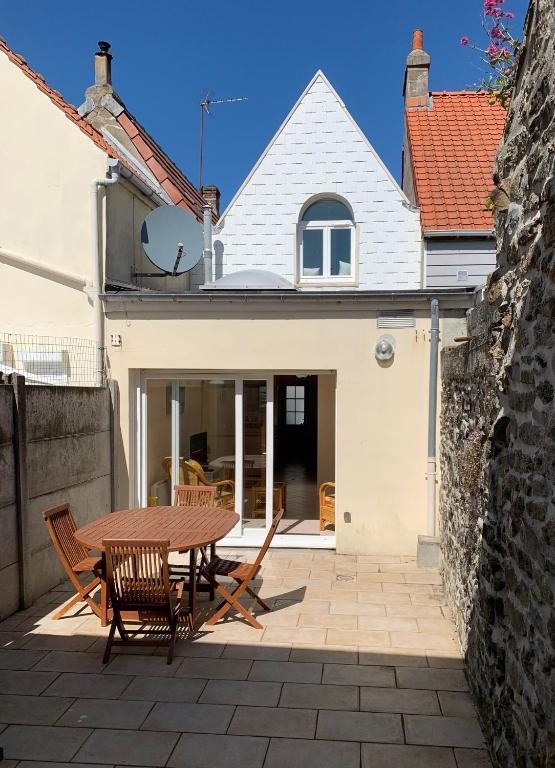 un patio avec une table et des chaises en bois dans l'établissement Villa Paul, à Wimereux