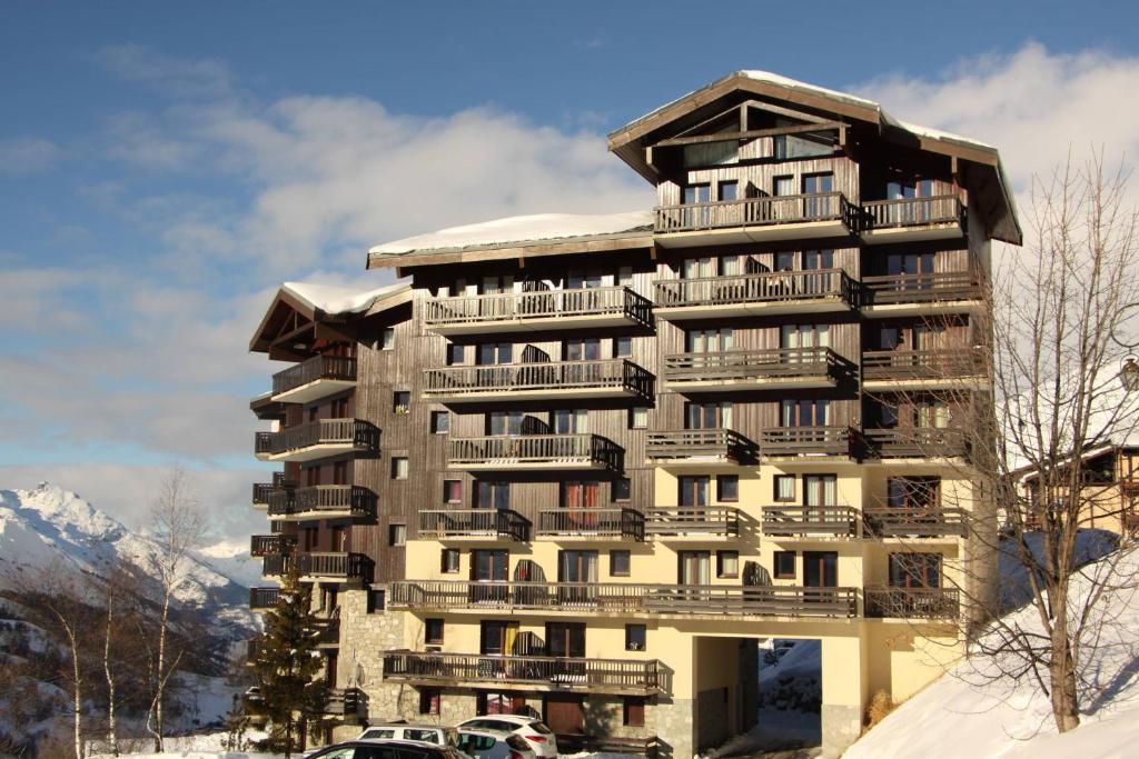 un grand bâtiment avec des voitures garées devant dans l'établissement travelski home classic - Résidence Les Balcons d'Olympie, aux Menuires