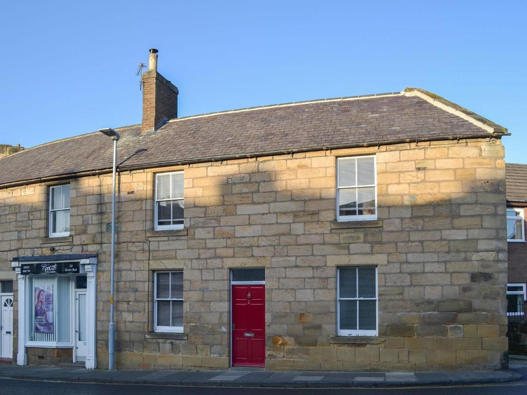 an old brick building with a red door at White Feathers in Alnwick