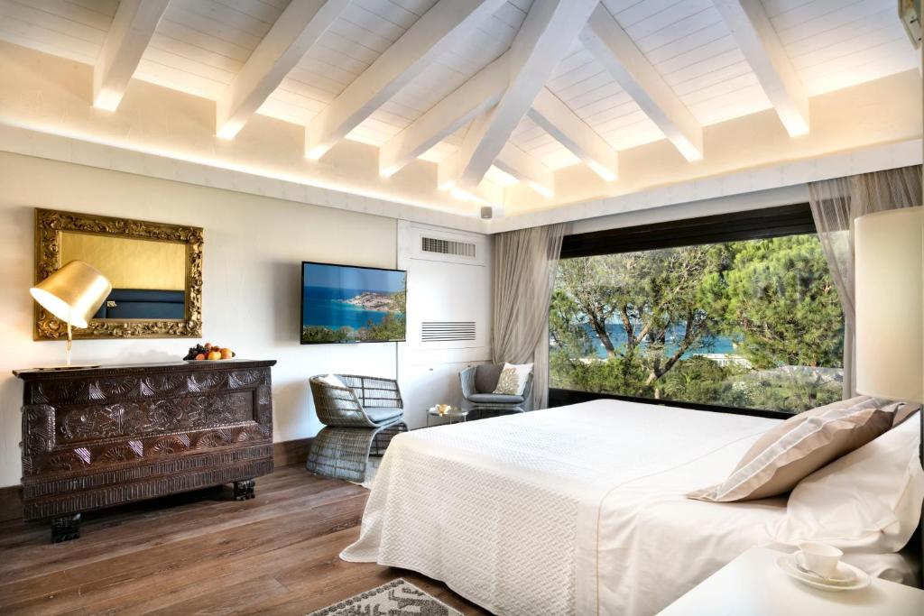 a bedroom with a large bed and a large window at Hotel Abi d'Oru in Porto Rotondo