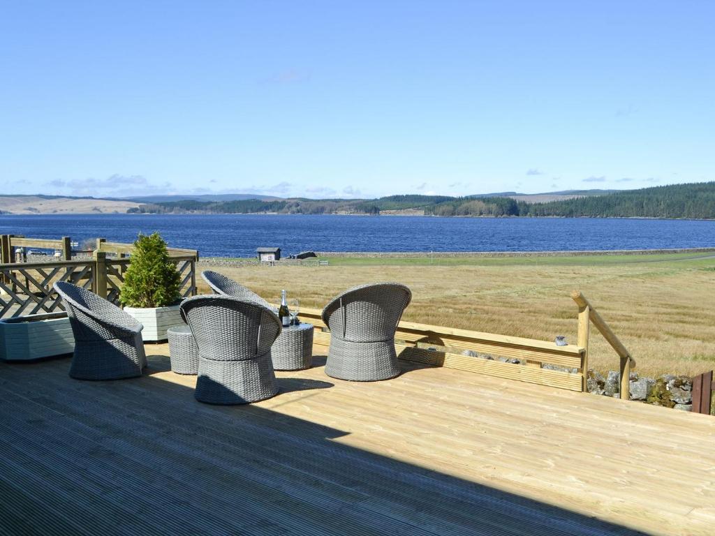 a deck with chairs and a view of the water at Lake View Cottage in Falstone