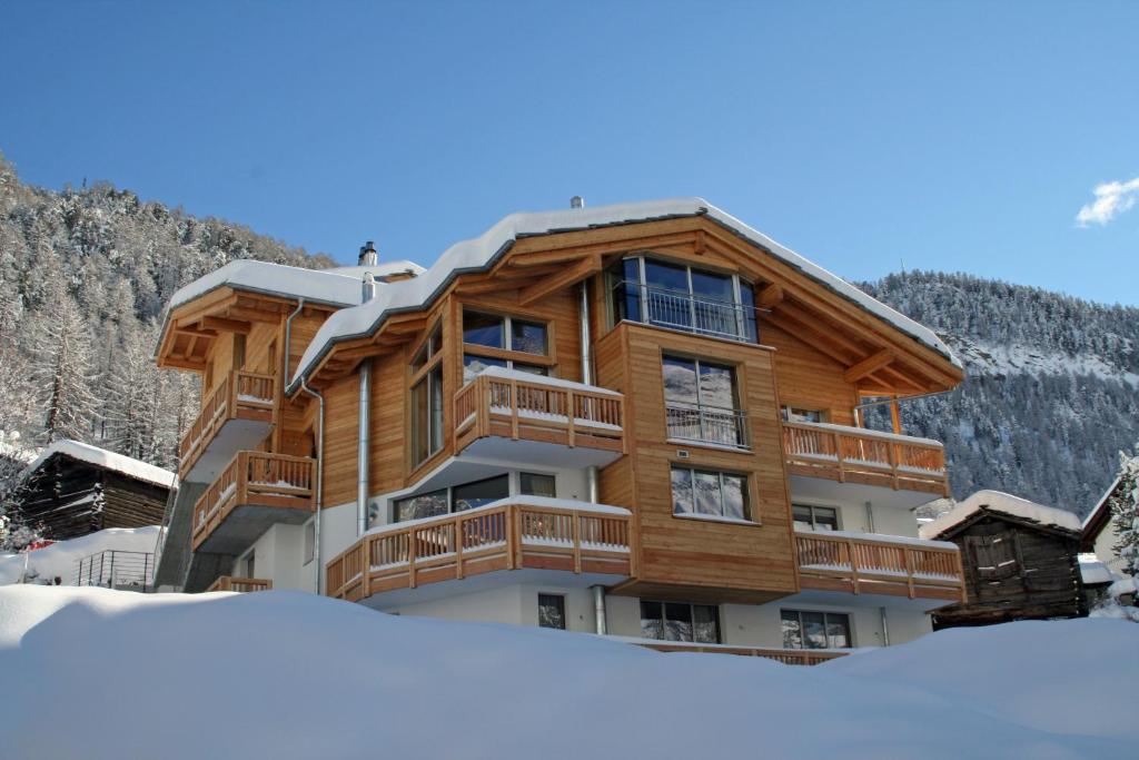 een groot houten gebouw met sneeuw ervoor bij Chalet Lea in Zermatt