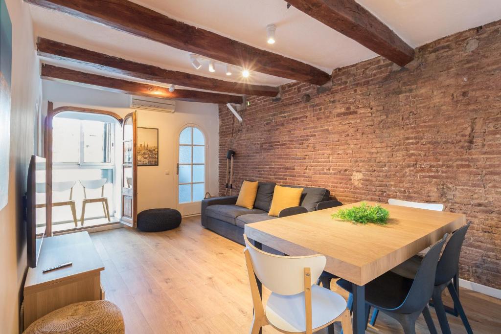 a living room with a wooden table and a brick wall at Precioso Apartamento en Mercat Sant Antoni in Barcelona