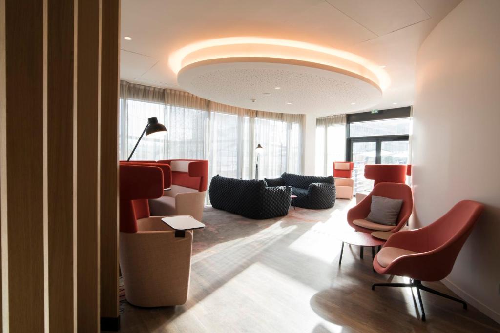 a lobby with a waiting room with red chairs at Holiday Inn Express - Paris - CDG Airport by IHG in Roissy-en-France