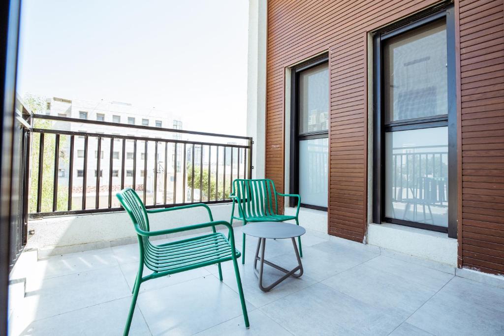 two chairs and a table on a balcony at הרצל בוטיק מבית דומוס - Herzl Boutique Apartments by Domus in Beer Sheva
