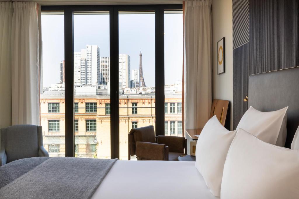 パリにあるQuinzerie hôtelのベッドと大きな窓が備わるホテルルームです。