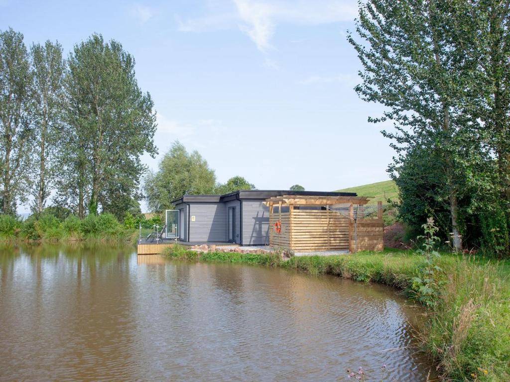 a house sitting on the side of a river at Kingfisher Lodge - Uk33889 in Cullompton