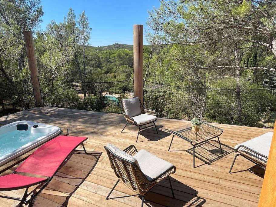 un patio con sillas y una terraza con bañera de hidromasaje. en Avignon : Le Mas Cott, le paradis dans la nature, en Aramon